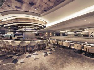 a restaurant with a bar with stools at Mercure Hangzhou West Lake in Hangzhou