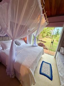 una camera con letto a baldacchino e finestra di Vila BeiradeiRô - Taipu de Fora a Taipu