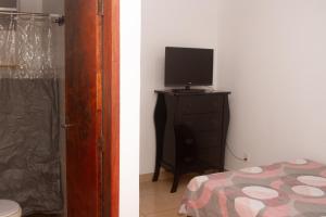 una camera da letto con un televisore su un comò con un letto di Casinha Vale do Sol a Nova Lima