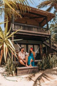 a man and woman sitting on the steps of a house at Pousada Fortal Jeri in Jericoacoara