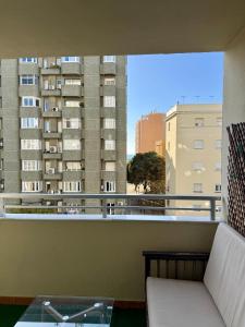 ein Balkon mit einer Couch und Blick auf ein Gebäude in der Unterkunft Grand Beachfront Apartament - Cadiz in Cádiz
