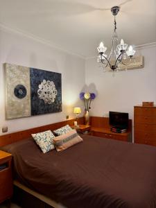 ein Schlafzimmer mit einem Bett und einem Kronleuchter in der Unterkunft Grand Beachfront Apartament - Cadiz in Cádiz