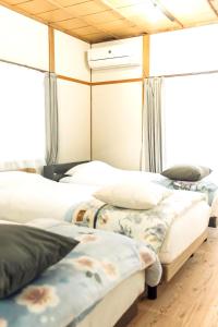 two beds in a room with windows at 隠れ古宿 おくゆかし in Beppu