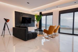 a living room with a couch and chairs and a television at You and the view in Mytilene