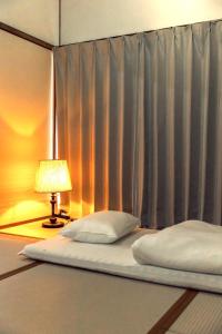 a bed with two pillows and a lamp next to a curtain at 隠れ古宿 おくゆかし in Beppu +11 photos