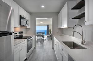 a kitchen with white cabinets and a sink and a table at Ocean Escape Boardwalk Oceanfront in Myrtle Beach