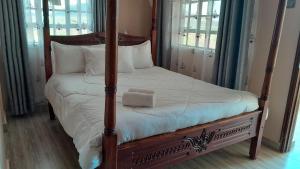 a bedroom with a four poster bed with white sheets at Ngelenyi Homes in Voi