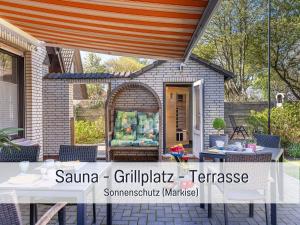 a patio with a table and an umbrella at Ferienwohnung KUMM RIN - Oase an der Nordsee in Carolinensiel