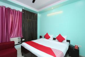 Hotel O Golden Palace في غازي آباد: غرفة نوم بسرير واريكة حمراء