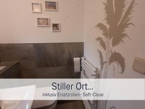 a bathroom with a palm tree stencil on the wall at Ferienwohnung KUMM RIN - Oase an der Nordsee in Carolinensiel