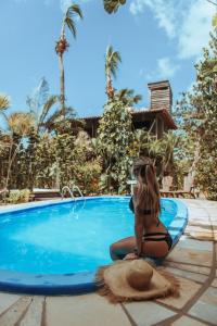 a woman in a bikini sitting on a surfboard by a swimming pool at Pousada Fortal Jeri in Jericoacoara