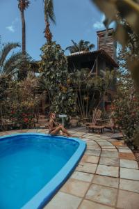 a woman sitting next to a swimming pool at Pousada Fortal Jeri in Jericoacoara