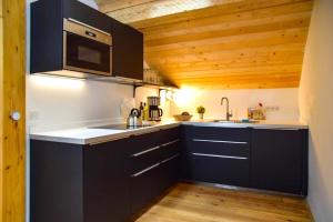 a kitchen with black cabinets and wooden ceilings at Spitzing Lodge Ferienwohnungen - Wanderparadies in den Bergen in Spitzingsee