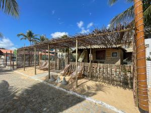 una casa de bambú con una hamaca delante de ella en Casa pé-na-areia c/ piscina e churrasqueira em Japaratinga, en Japaratinga