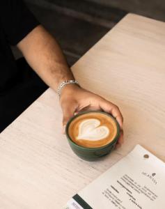 a person holding a cup of coffee on a table at XTILU Hotel - Adults only - in Oaxaca City