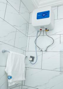 DPE Apartments في كوماسي: حمام أبيض مع منشفة بيضاء وكاميرا على الحائط