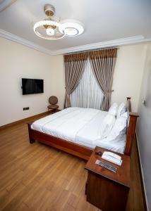 DPE Apartments في كوماسي: غرفة نوم بسرير وطاولة وتلفزيون