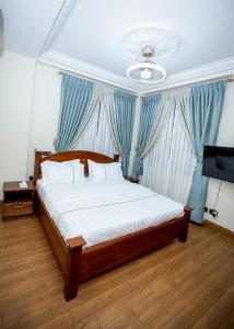 DPE Apartments في كوماسي: غرفة نوم بسرير كبير مع ستائر زرقاء