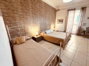ein Schlafzimmer mit zwei Betten und einer Ziegelwand in der Unterkunft Ortilì in Syrakus