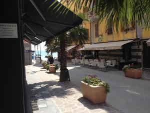 una calle con mesas y sillas y una sombrilla negra en Appartamento Regonini, en Alassio