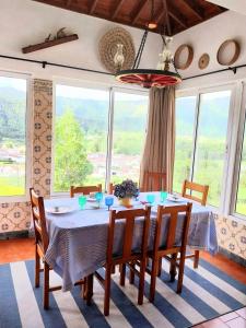 Un comedor con mesa y sillas y ventanas. en Casa da Belavista, en Furnas