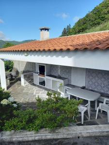 Un patio con mesa y sillas y un edificio. en Casa da Belavista, en Furnas