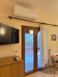 Lykno Pozar في كاتو لوتراكي: غرفة معيشة مع تلفزيون وباب زجاجي منزلق