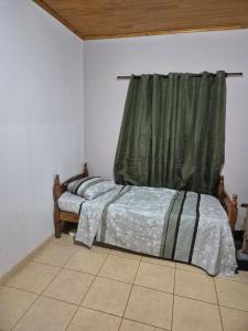 Un dormitorio con una cama y una cortina verde. en Descanso Guazú, en Posadas 6 fotos más