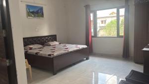Un dormitorio con una cama en una habitación con ventana. en Aroha home stay, en Pālampur