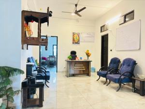 una sala de espera con sillas azules y escritorio en Aroha home stay, en Pālampur