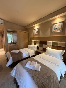 Una habitación de hotel con tres camas con sábanas blancas. en Lux Apartment in Dreamland Oasis, en Chakvi