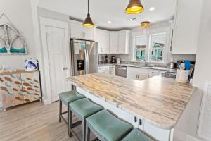 una cocina con armarios blancos y una barra grande con taburetes en CP117B - Sunrise Promise, en Kill Devil Hills