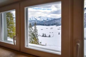 a window with a view of a snowy mountain at Spitzing Lodge Ferienwohnungen - Wanderparadies in den Bergen in Spitzingsee