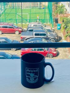 a coffee cup on a window sill with cars in a parking lot at Simplistic Ambience At The Lekki Peninsula, Lagos in Mama