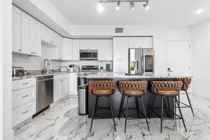 Una cocina con gabinetes blancos y taburetes de bar. en RIVER FLY IN Coastal Penthouse Panoramic Views RFI 3BR KQQ Pano, en Audubon