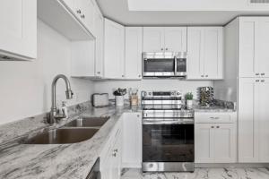 Una cocina blanca con gabinetes blancos y un fregadero. en RIVER FLY IN Coastal Penthouse Panoramic Views RFI 3BR KQQ Pano, en Audubon