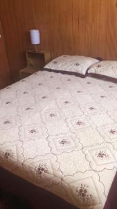 Cabañas Mami Kiki 2 في بانغويبولي: سرير مع لحاف أبيض عليه زهور