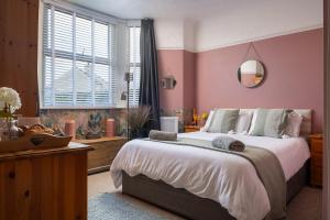a bedroom with a large bed with pink walls at Heligog at Deanfield House Moelfre Sea view adult only appartment in Moelfre in Moelfre