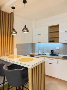 a kitchen with white cabinets and a table with chairs at Prestige Forest Resort Zlatibor Wellness & Spa in Zlatibor