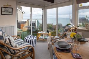 a living room with a table and chairs and windows at Heligog at Deanfield House Moelfre Sea view adult only appartment in Moelfre in Moelfre