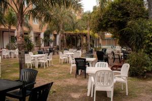 a group of tables and chairs in a yard with palm trees at Grand Hotel Principado in Termas de Río Hondo +10 photos
