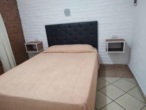 a bedroom with a bed with a black headboard and two tables at Lo de Vlady in Mina Clavero