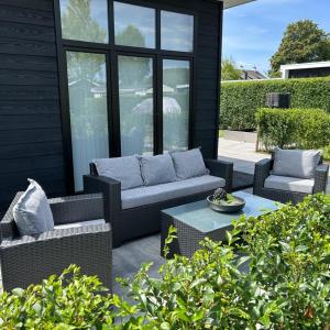 a patio with two couches and a table at Luxus Chalet Time Out De Veerstal in Lathum