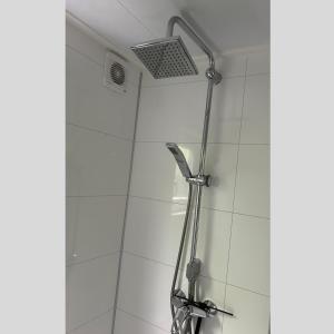 a shower with a shower head on a white tile wall at Luxus Chalet Time Out De Veerstal in Lathum +14 photos