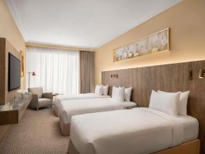 Una habitación de hotel con tres camas y un televisor. en Movenpick Hotel & Residences Hajar Tower Makkah, en La Meca