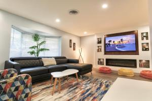 Una sala de estar con un sofá negro y un televisor. en Poolside Paradise Clearwater Family Friendly House, en Clearwater