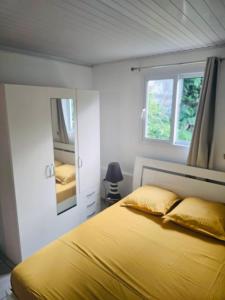 a bedroom with a yellow bed and a mirror at Chez Pascal in Terre-de-Haut