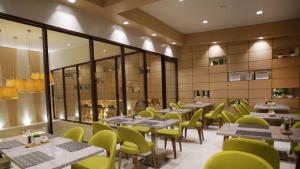 a restaurant with tables and yellow chairs and windows at Watergate Boutique Hotel in Butuan