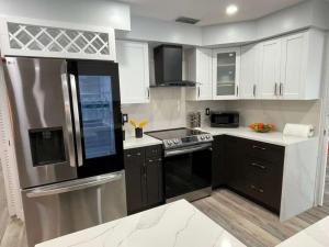 Una cocina con electrodomésticos de acero inoxidable y gabinetes blancos. en Poolside Paradise Clearwater Family Friendly House, en Clearwater