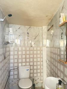 a white tiled bathroom with a toilet and a sink at Talia Surf Morocco in Taghazout +50 photos
